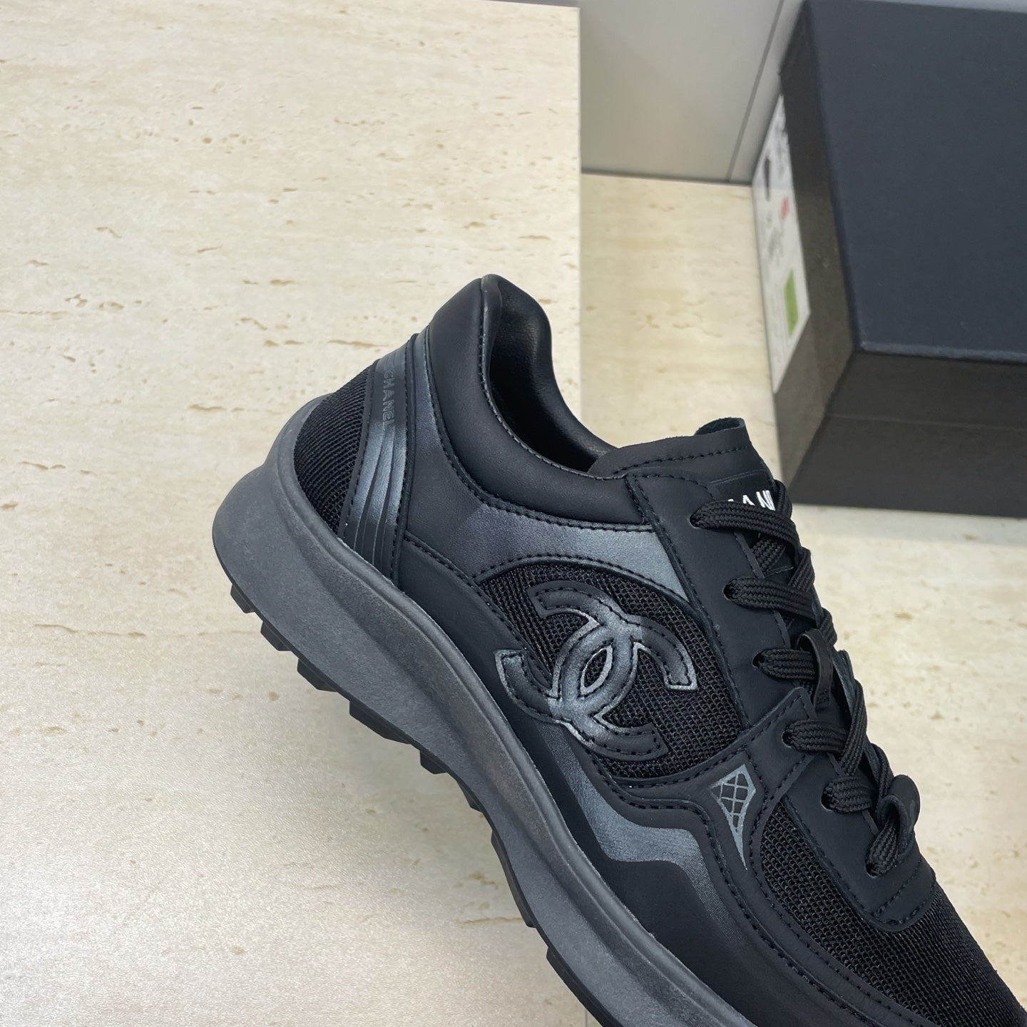 Chanel unisex sneaker quarter view in dark mesh with lace-up and signature CC detail