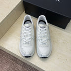 White Chanel unisex lace-up sneakers, front view with stitched logo accents