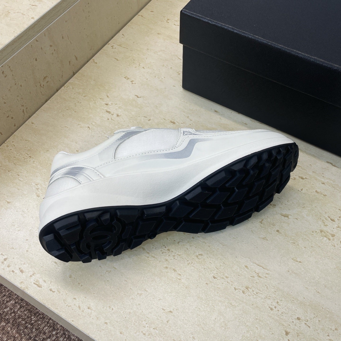 White Chanel unisex sneakers, outsole tread view with dark rubber pattern