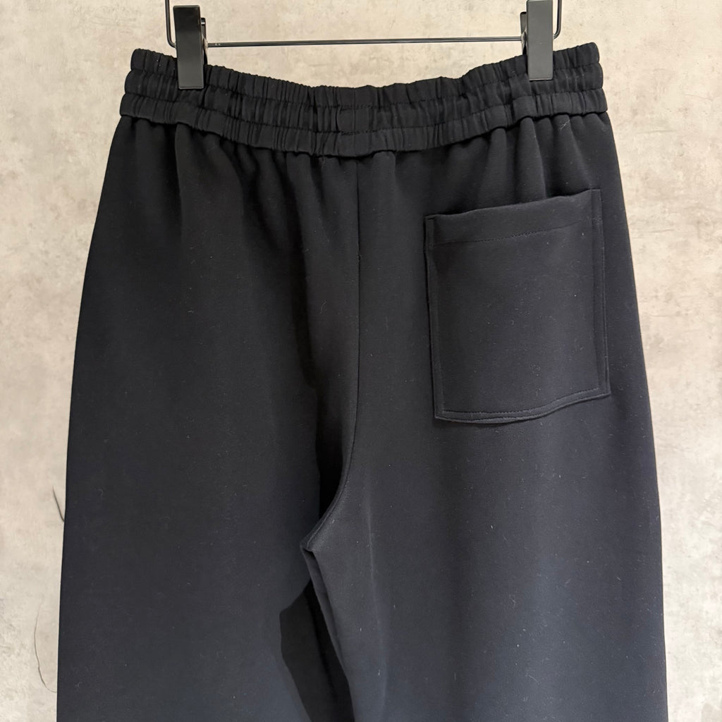 Black elastic-waist pants with front patch pocket and smooth front panel