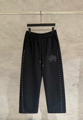 Black wide-leg pants with drawstring waist and side stud trim, embroidered cross patch