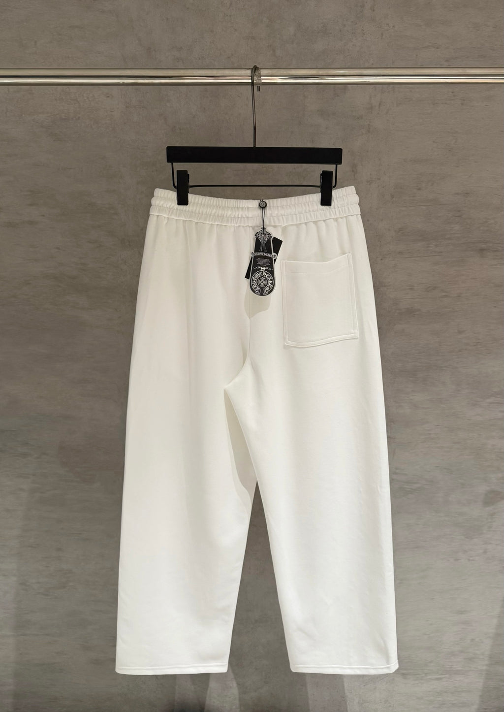 White cropped pants with elastic waist, side pockets, and hanging brand tag