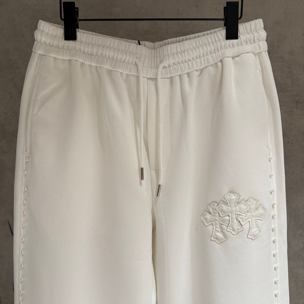 White cropped pants close-up of elastic waistband and decorative cross applique
