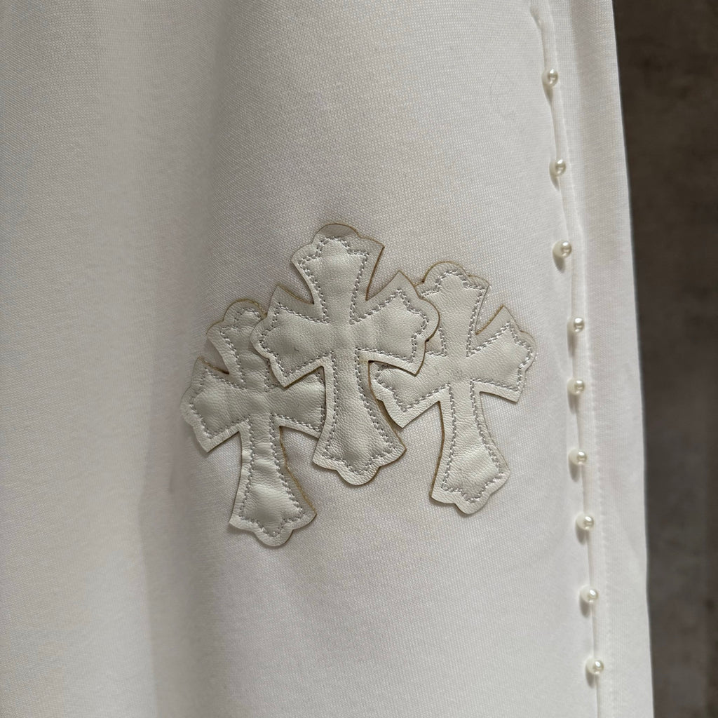 White fabric detail with stitched cross applique and small stud accents