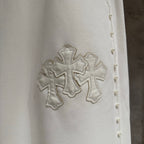 White fabric detail with stitched cross applique and small stud accents