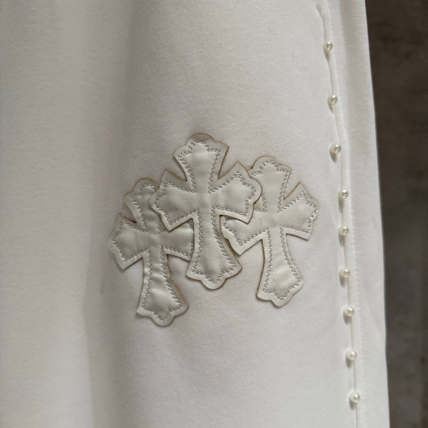 White fabric detail with stitched cross applique and small stud accents