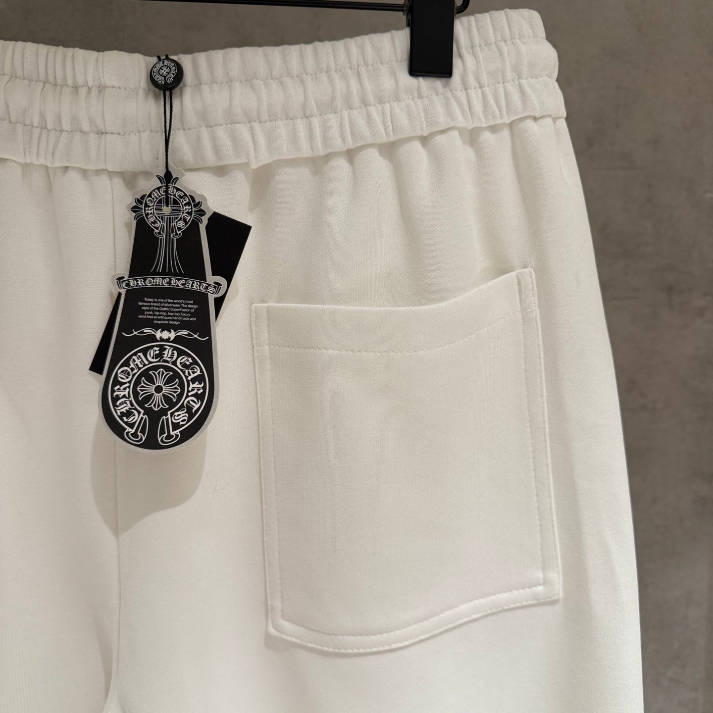 White cropped pants with elastic waist, side pocket, and hanging label on strings