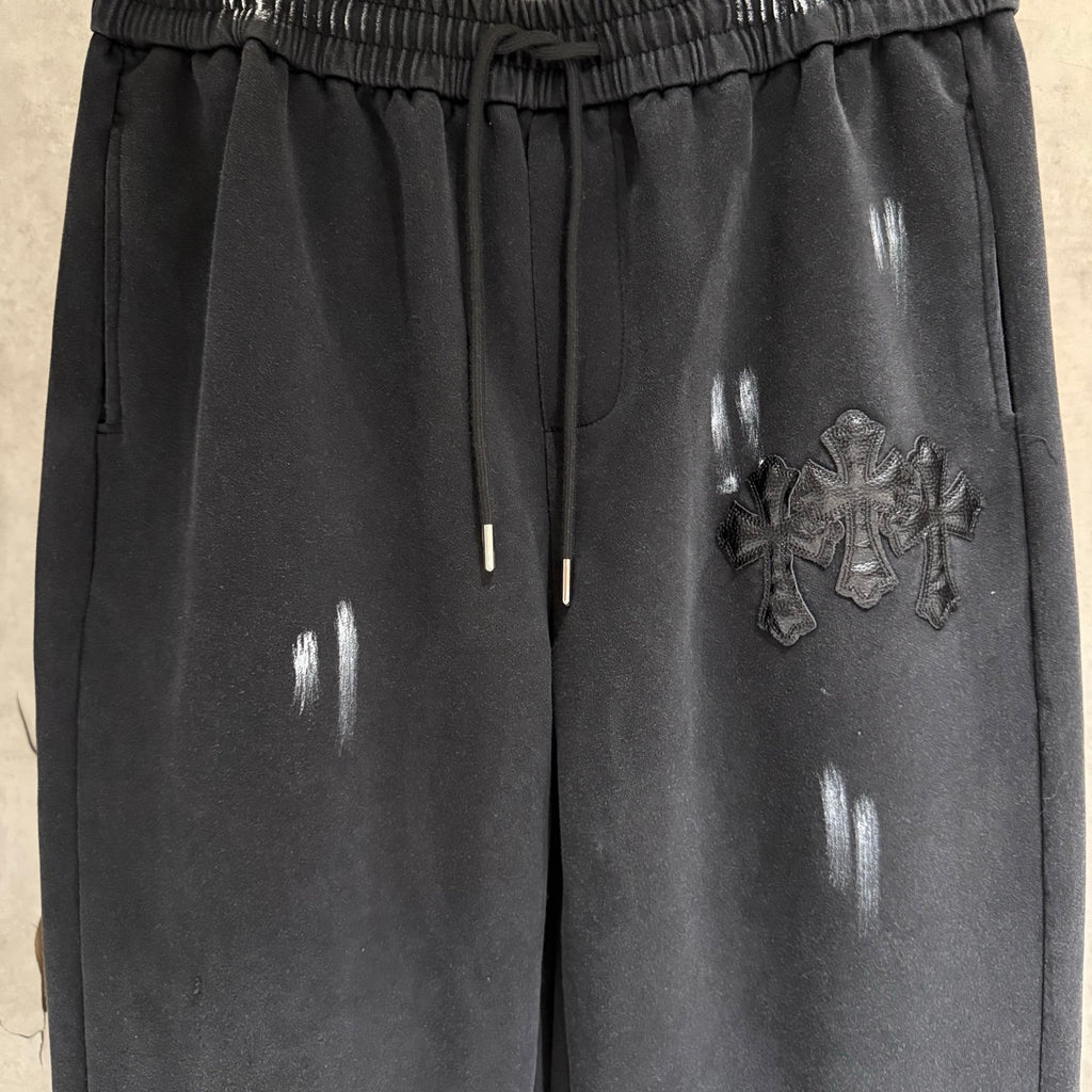 Dark pants with elastic waist and drawstring, front patch emblem and glossy spots