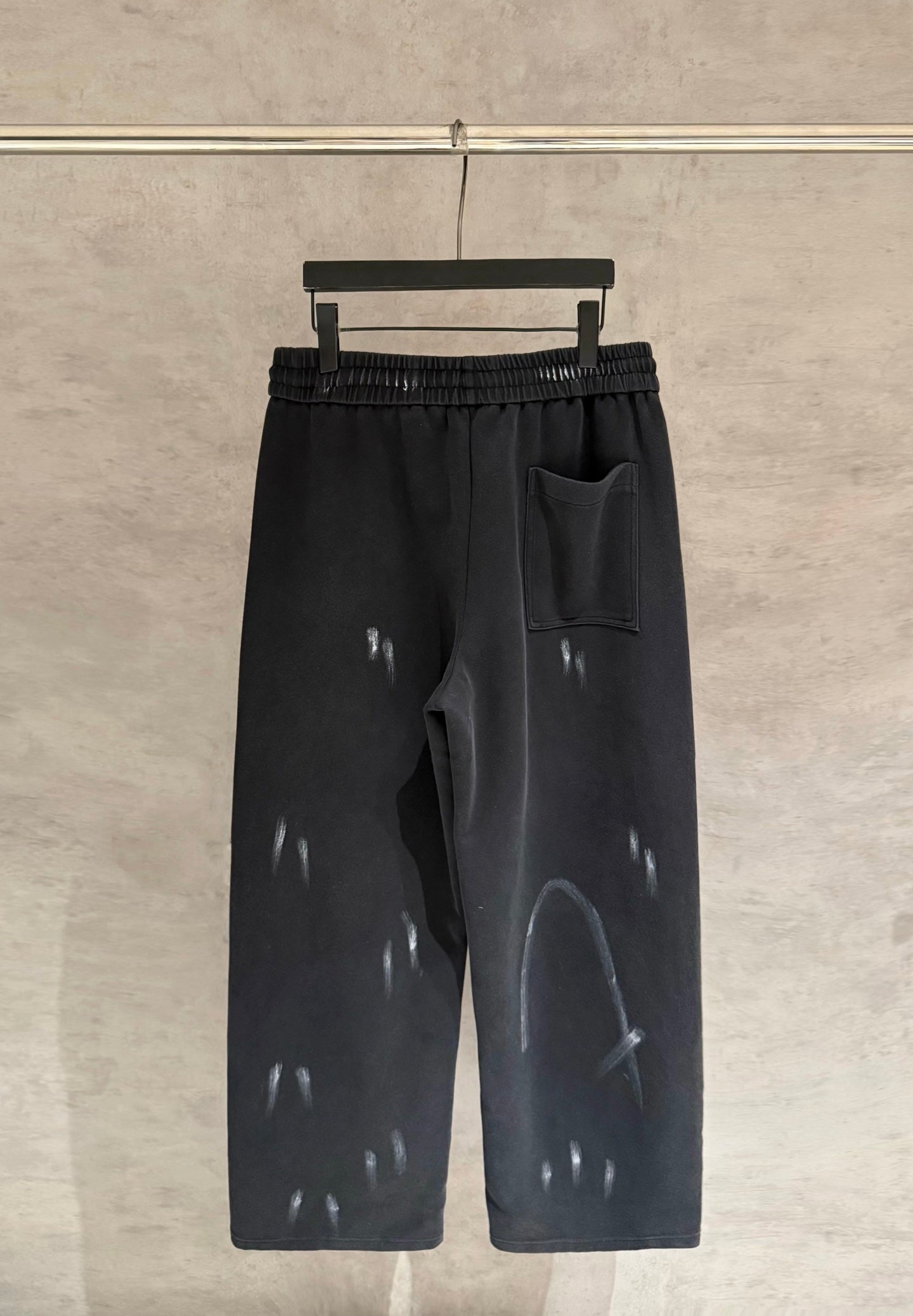 Black wide-leg pants with elastic waist, side pocket, and glossy scattered marks