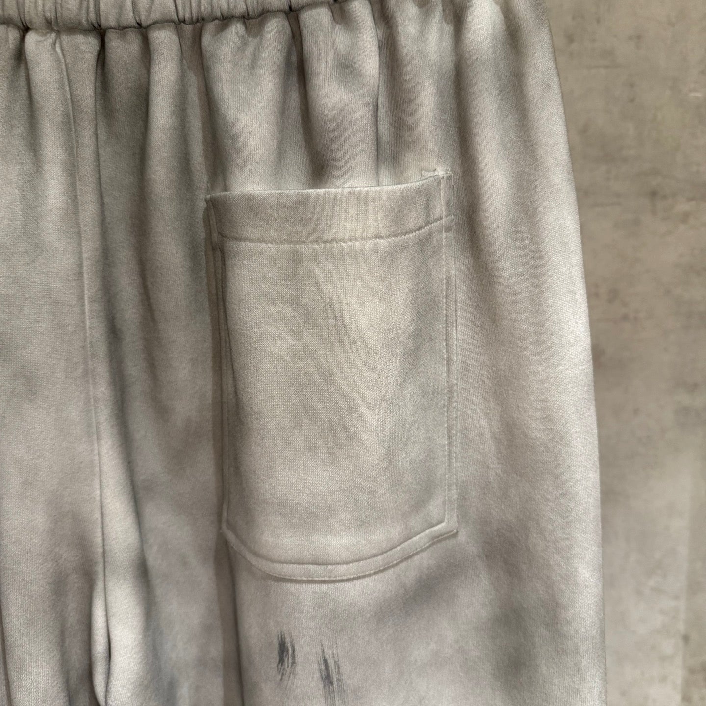 Light gray Chrome pants close-up: front patch pocket and elastic waistband
