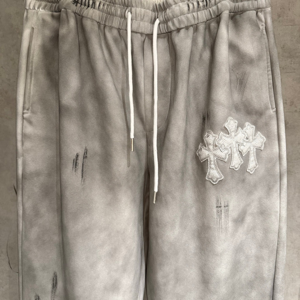 Chrome pants close-up: elastic waist, drawstrings, and silver cross patch