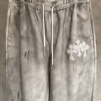 Chrome pants close-up: elastic waist, drawstrings, and silver cross patch