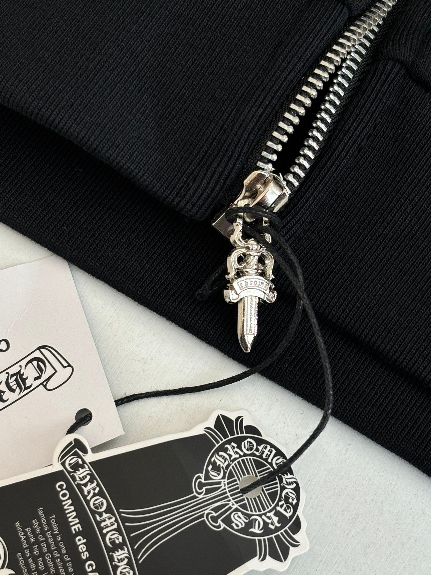 Black hoodie cuff with ribbed knit and silver zipper pull with charm