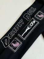Black hoodie sleeve detail with white text, stitched-style graphics, and pink accents