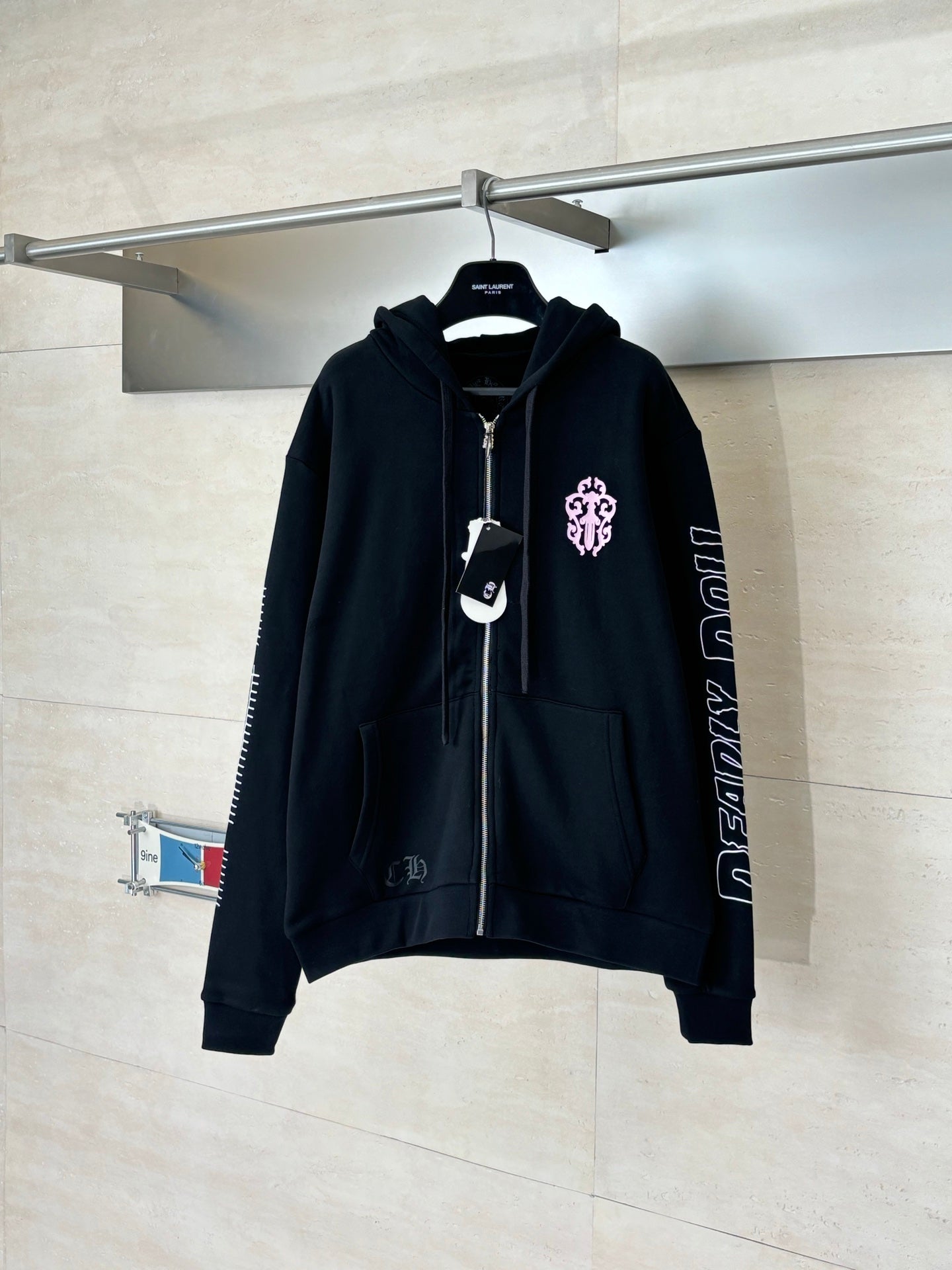 Black zip-up hoodie with hood, front zipper, and pink crest graphic on left chest
