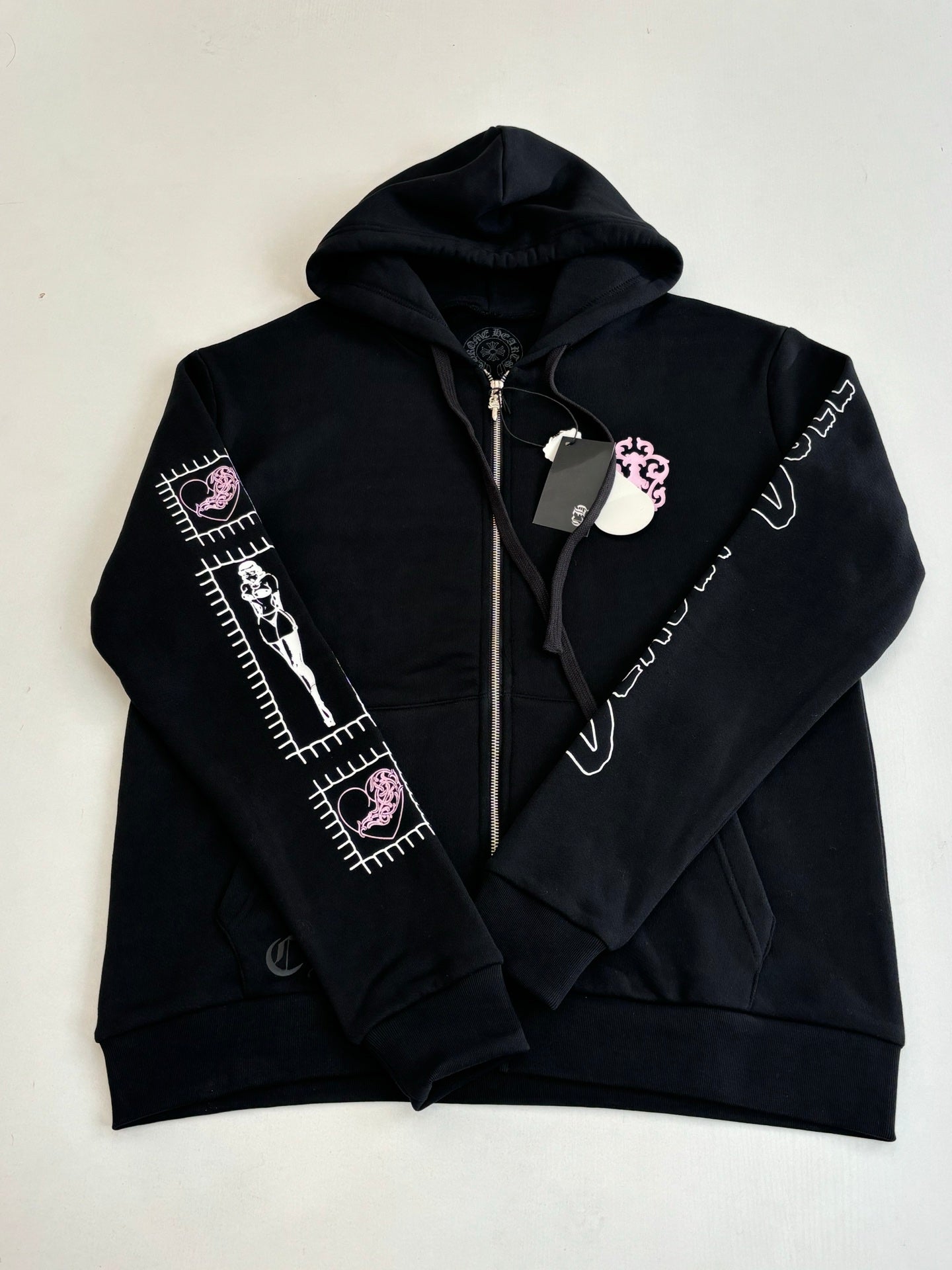 Black zip-up hoodie with hood, front zipper, and sleeve graphic stripes in white and pink