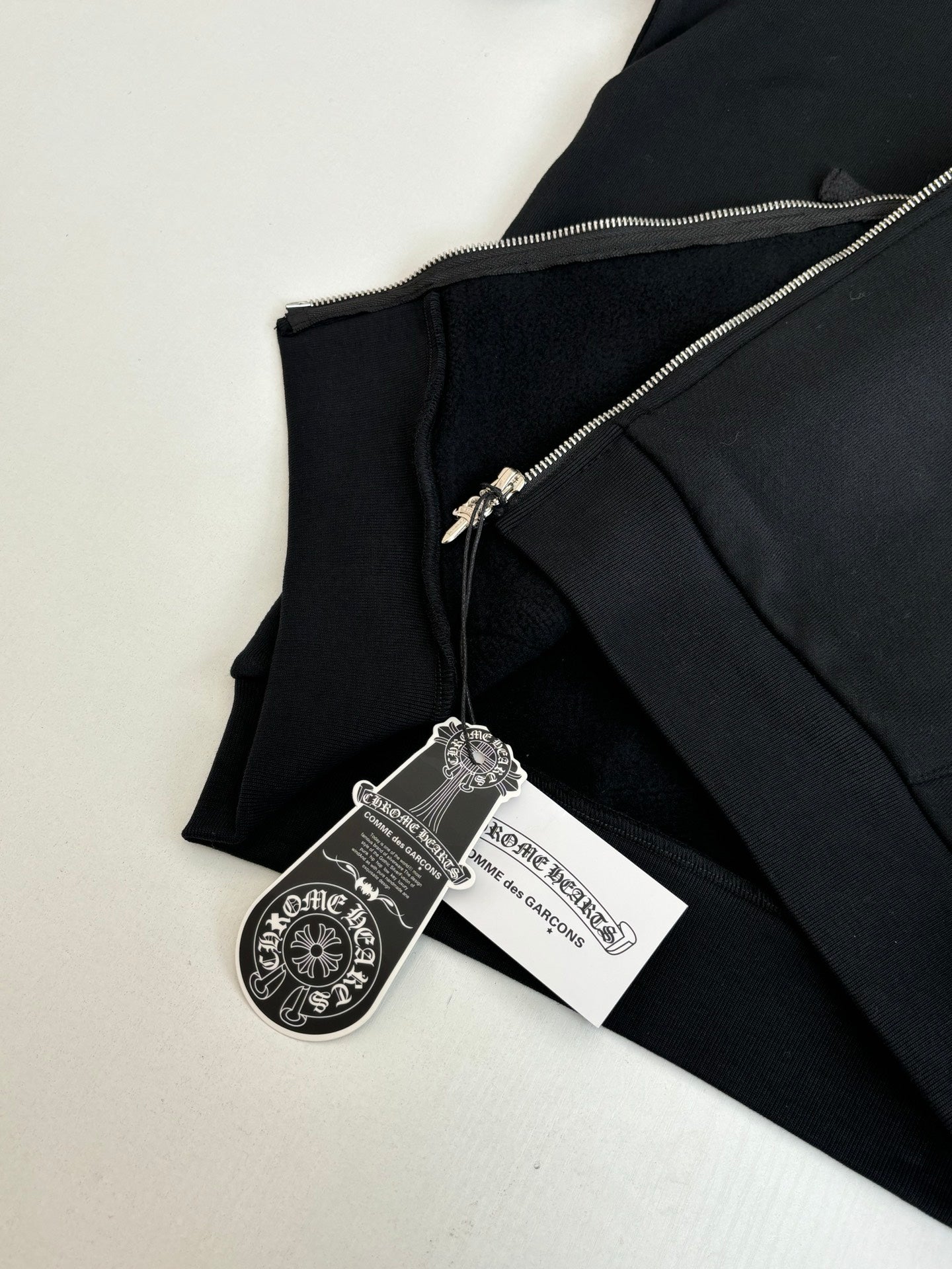 Black hoodie close-up with metal zipper and hanging brand tags