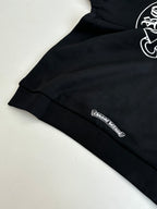 Black long-sleeve top with small logo patch near hem