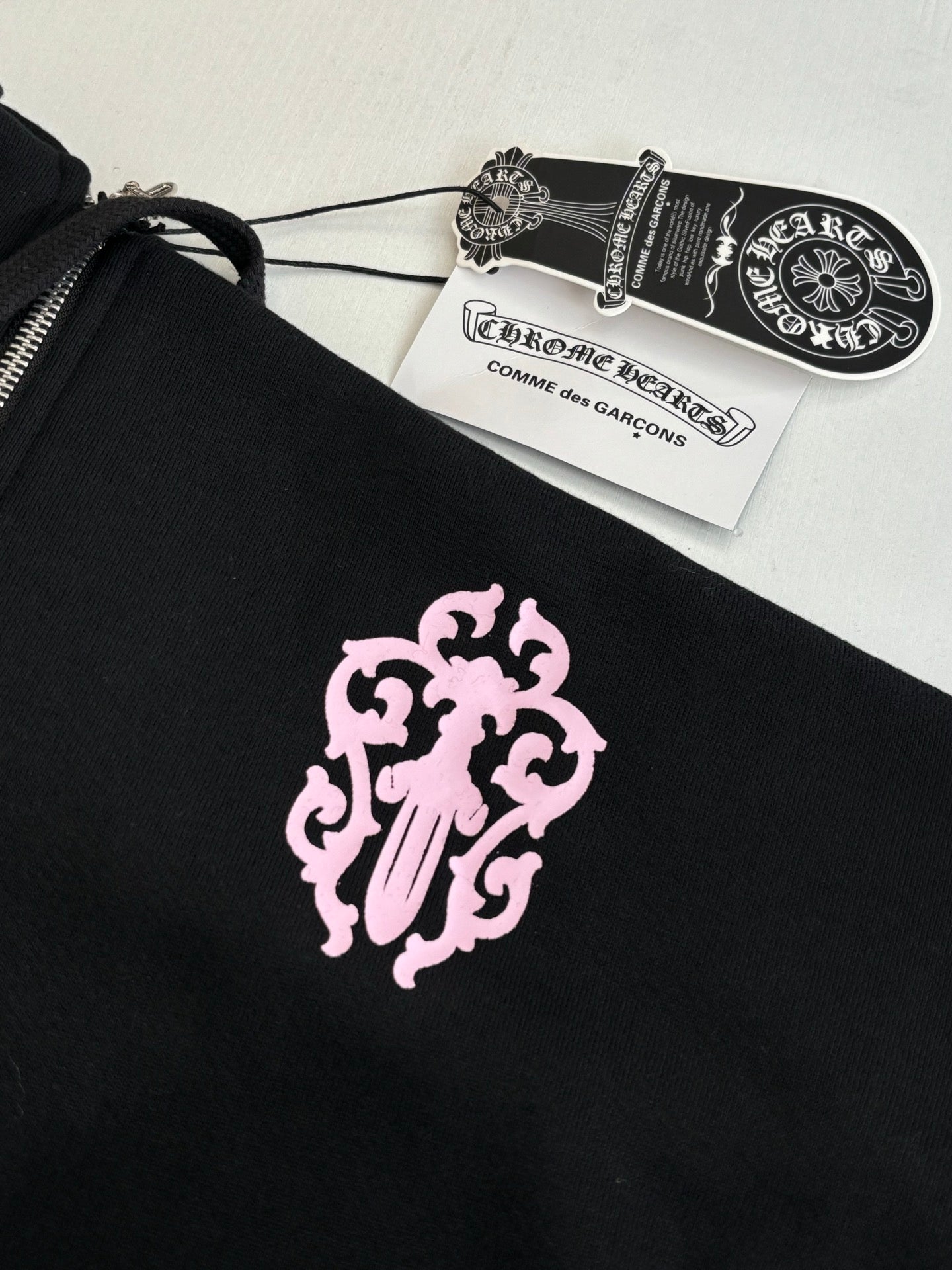 Black hoodie front with pink lion crest graphic and hanging price tag