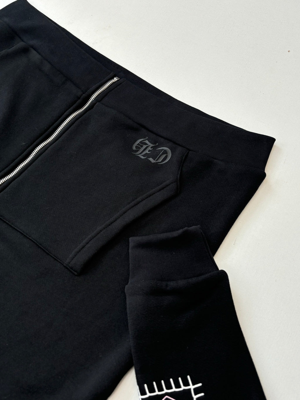 Black hoodie with side seam pocket and small embroidered logo patch