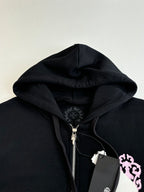 Black hoodie with hood and front zipper, close-up of crest patch and pink graphic