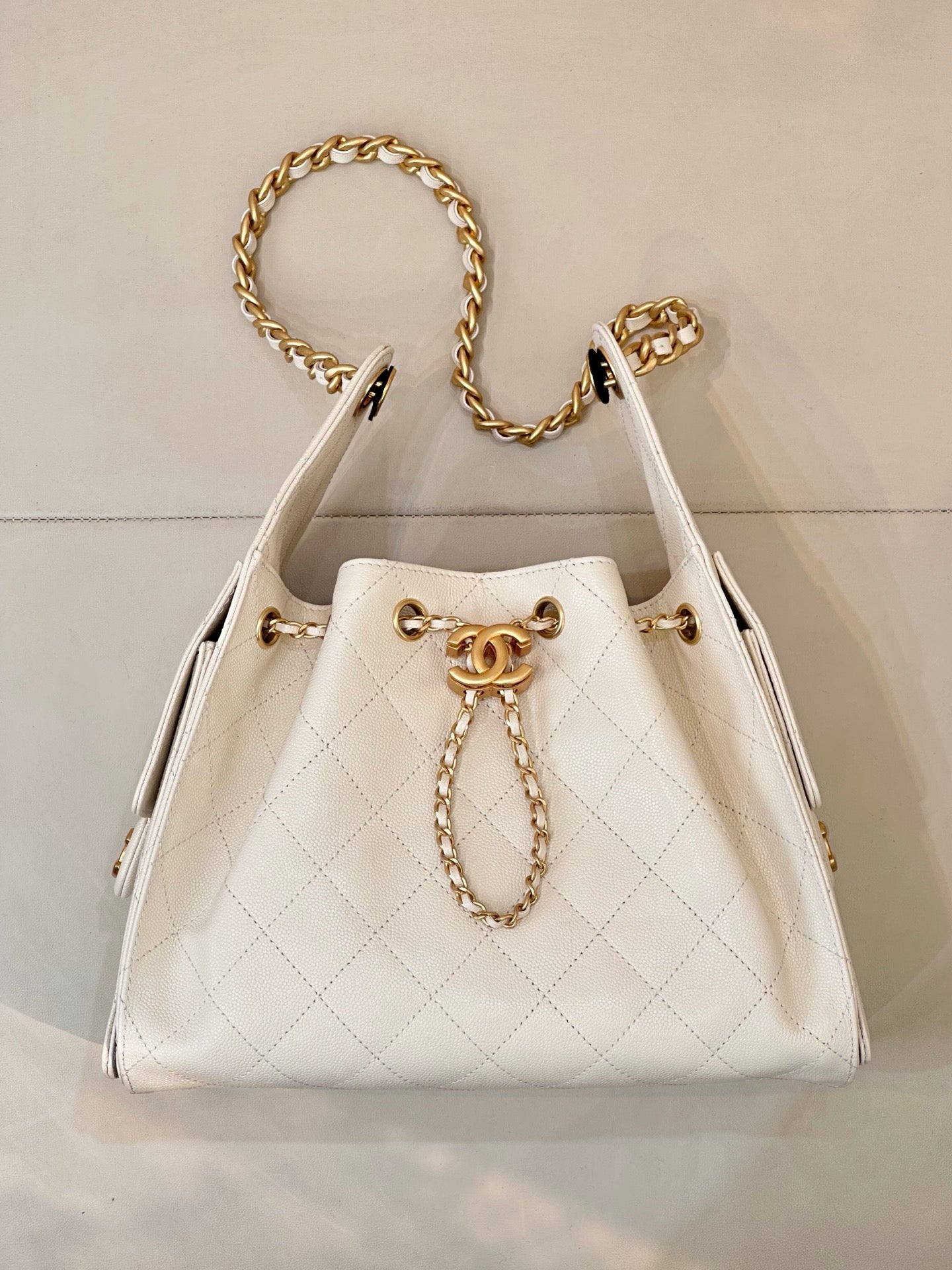 Chanel quilted white leather bucket bag with gold chain handles and CC charm center front