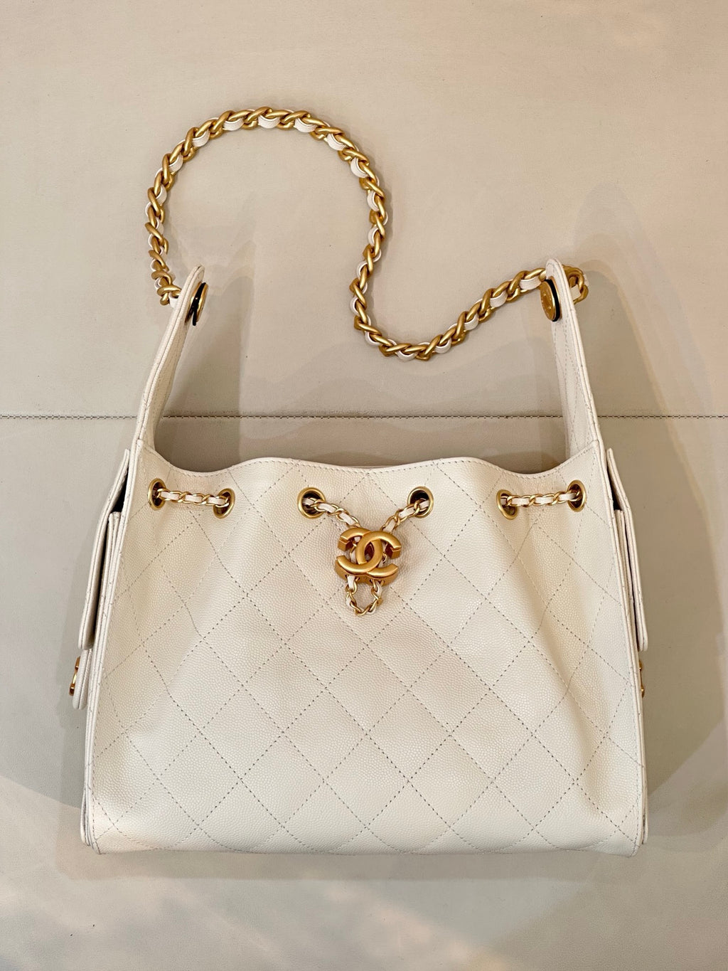 Chanel quilted white leather bucket bag with open top and gold chain handles, CC logo front