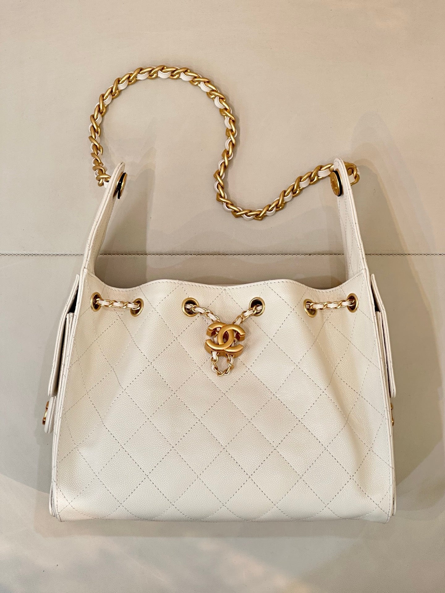 Chanel quilted white leather bucket bag with open top and gold chain handles, CC logo front