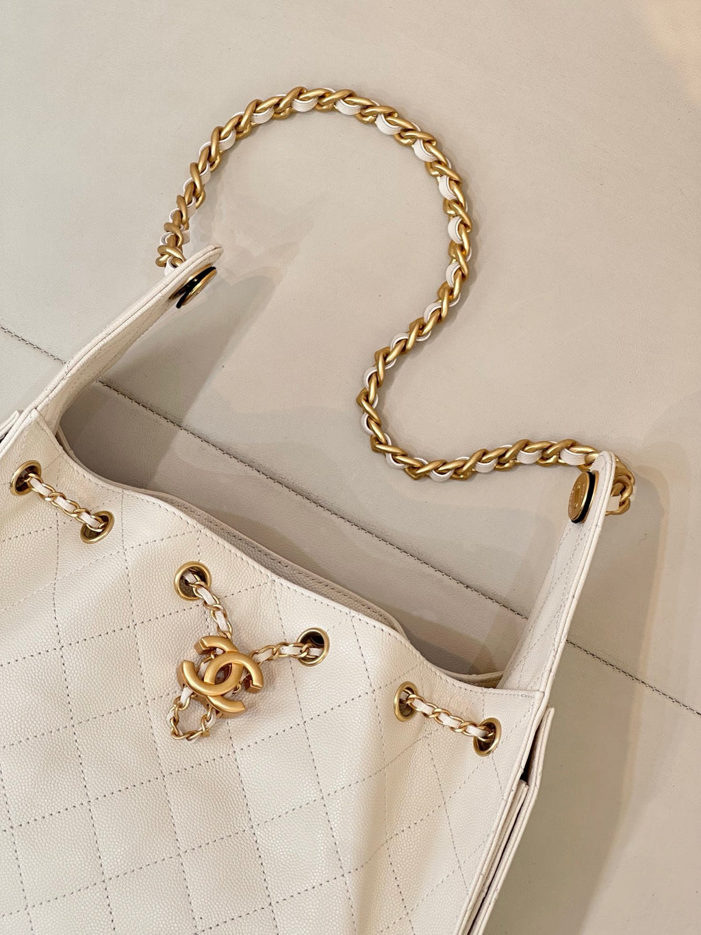 Chanel quilted white leather bucket bag with gold chain strap and CC logo on front panel