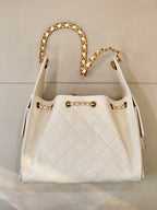 Chanel quilted white leather bucket bag with open top, gold chain strap, and CC logo detail