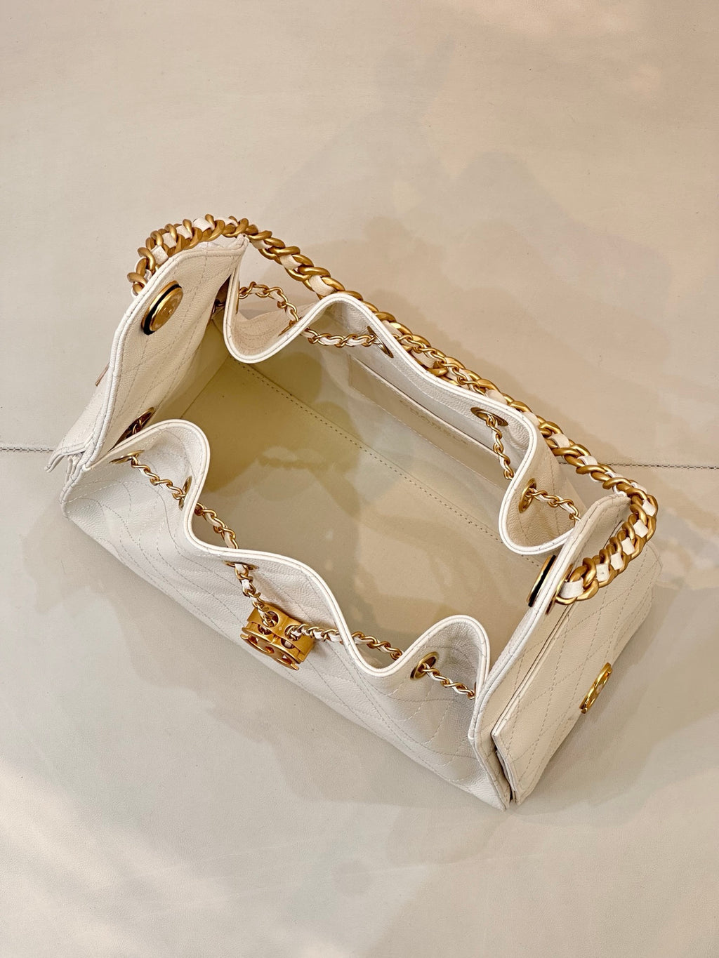 Chanel quilted white leather bucket bag open view with gold chain strap and interior lining