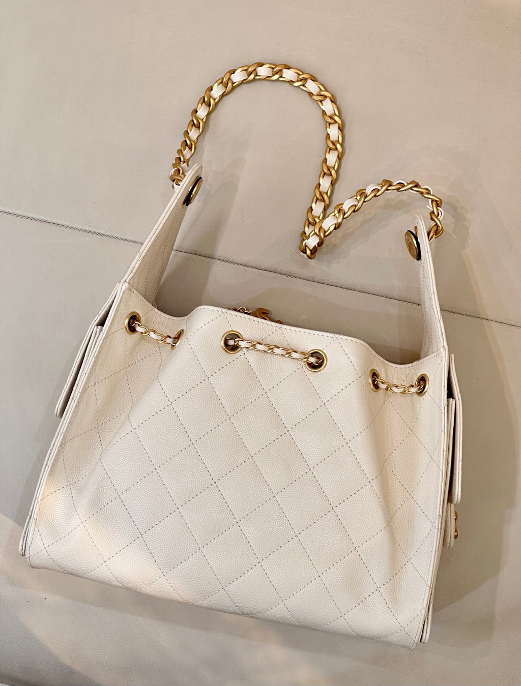 Chanel quilted white leather bucket bag with gold chain handles and front CC logo hardware