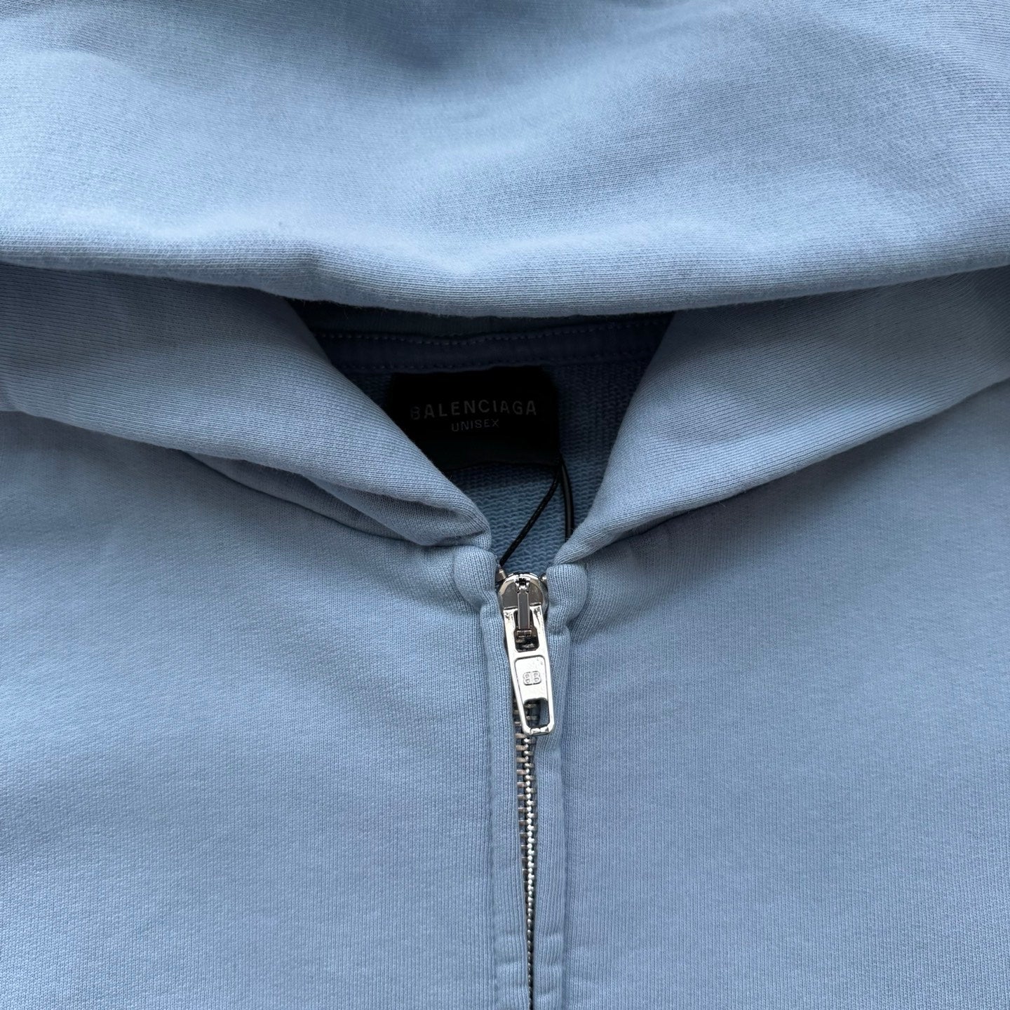 Balenciaga light blue hoodie close-up with silver zipper and inner label