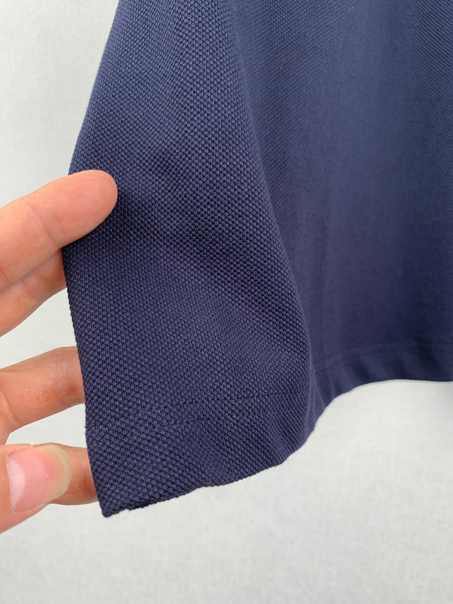 Navy polo shirt sleeve fabric, showing knit texture and hem
