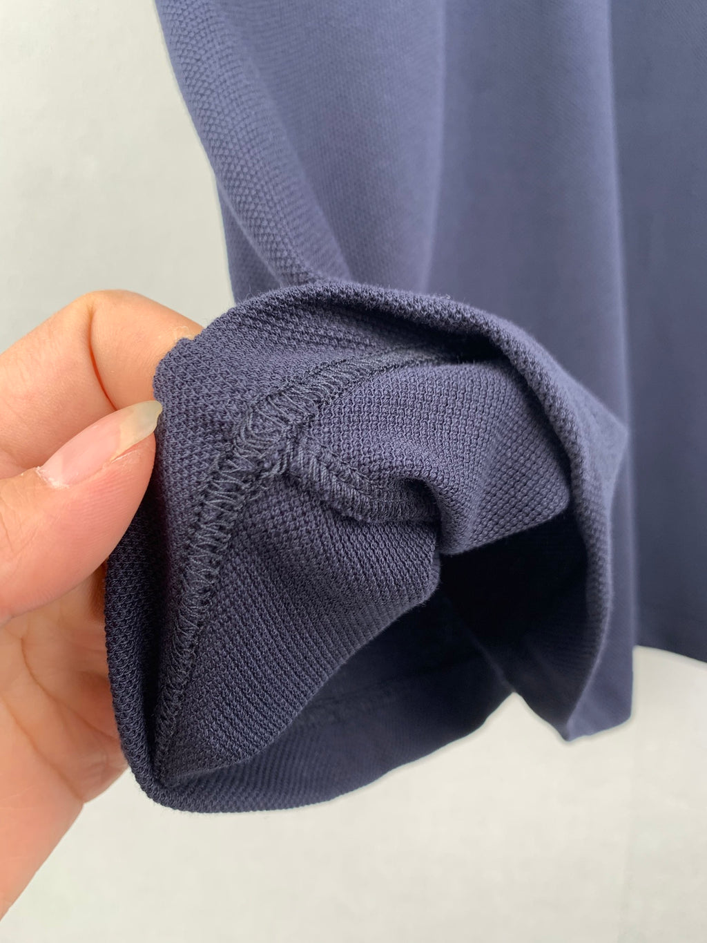 Navy polo shirt cuff and sleeve opening, knit texture shown by hand