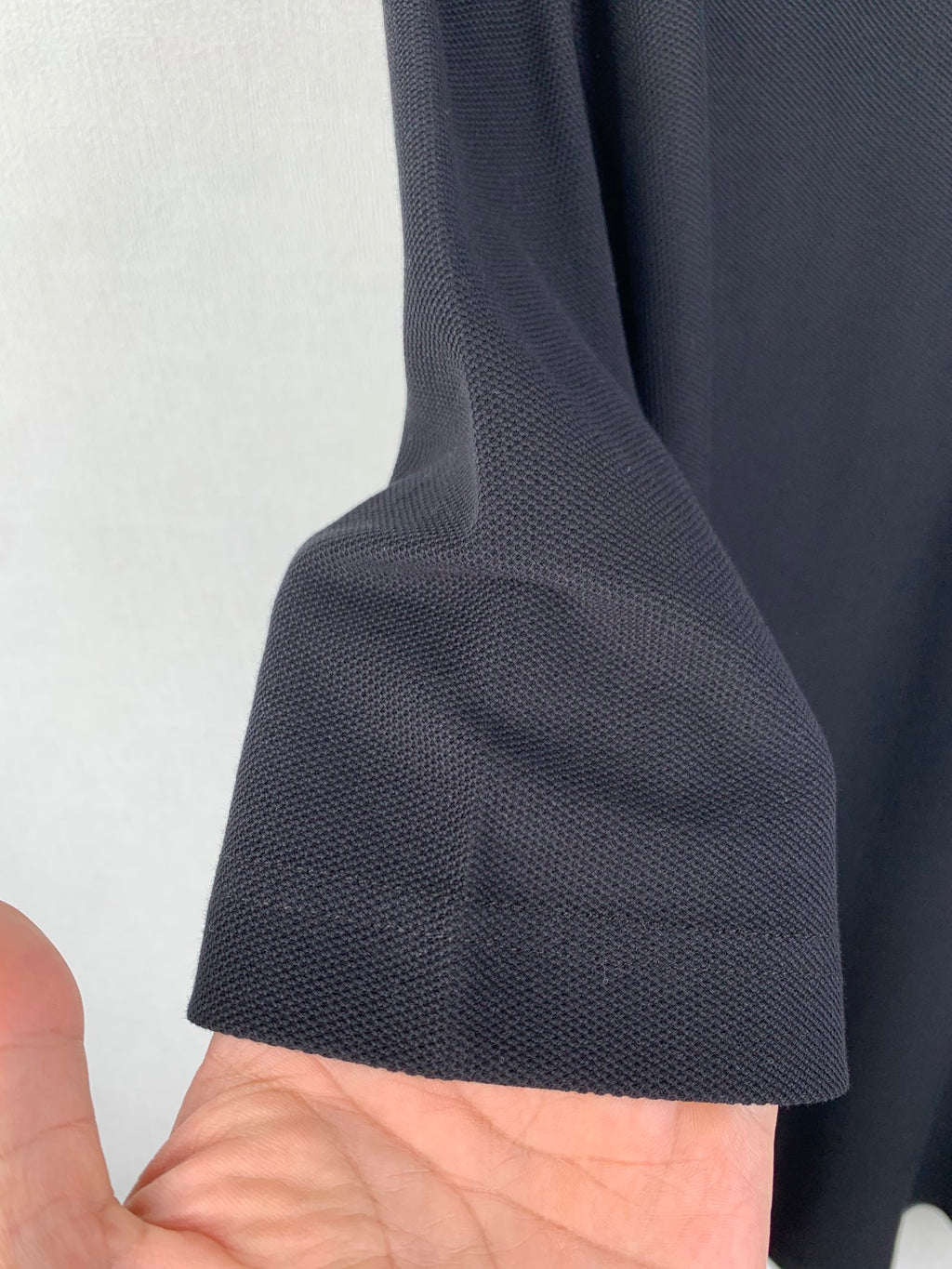Navy polo shirt sleeve cuff detail with textured fabric and short sleeve hem