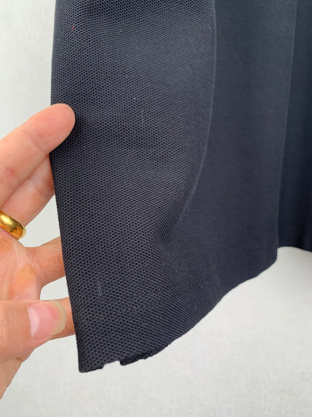 Navy polo shirt fabric close-up with stitched seam along sleeve edge