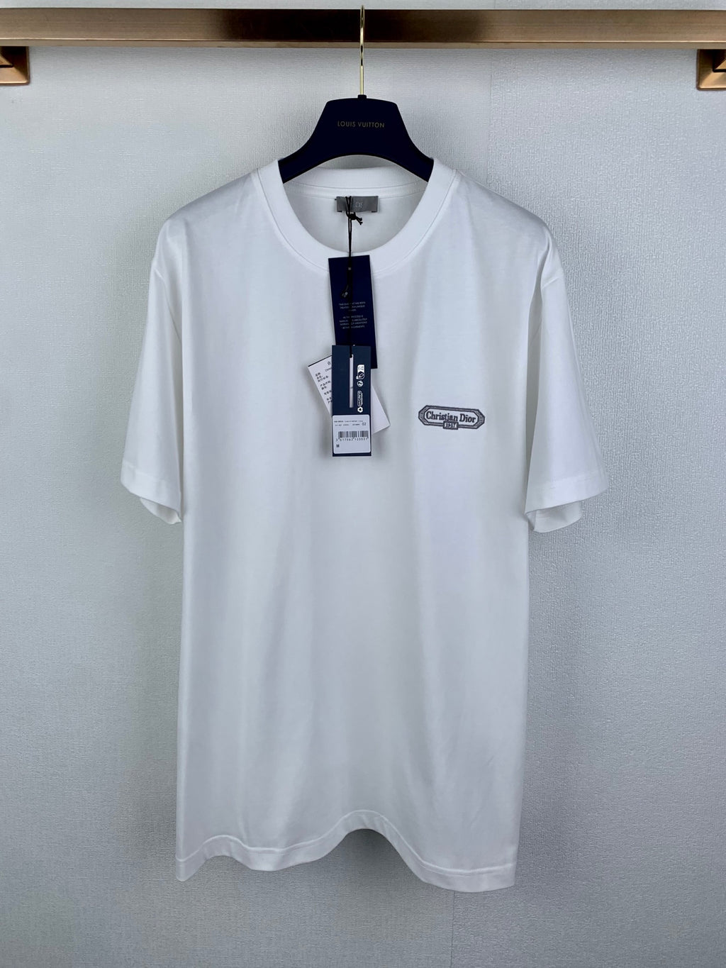 White short-sleeve T-shirt with Dior logo chest patch, on a hanger