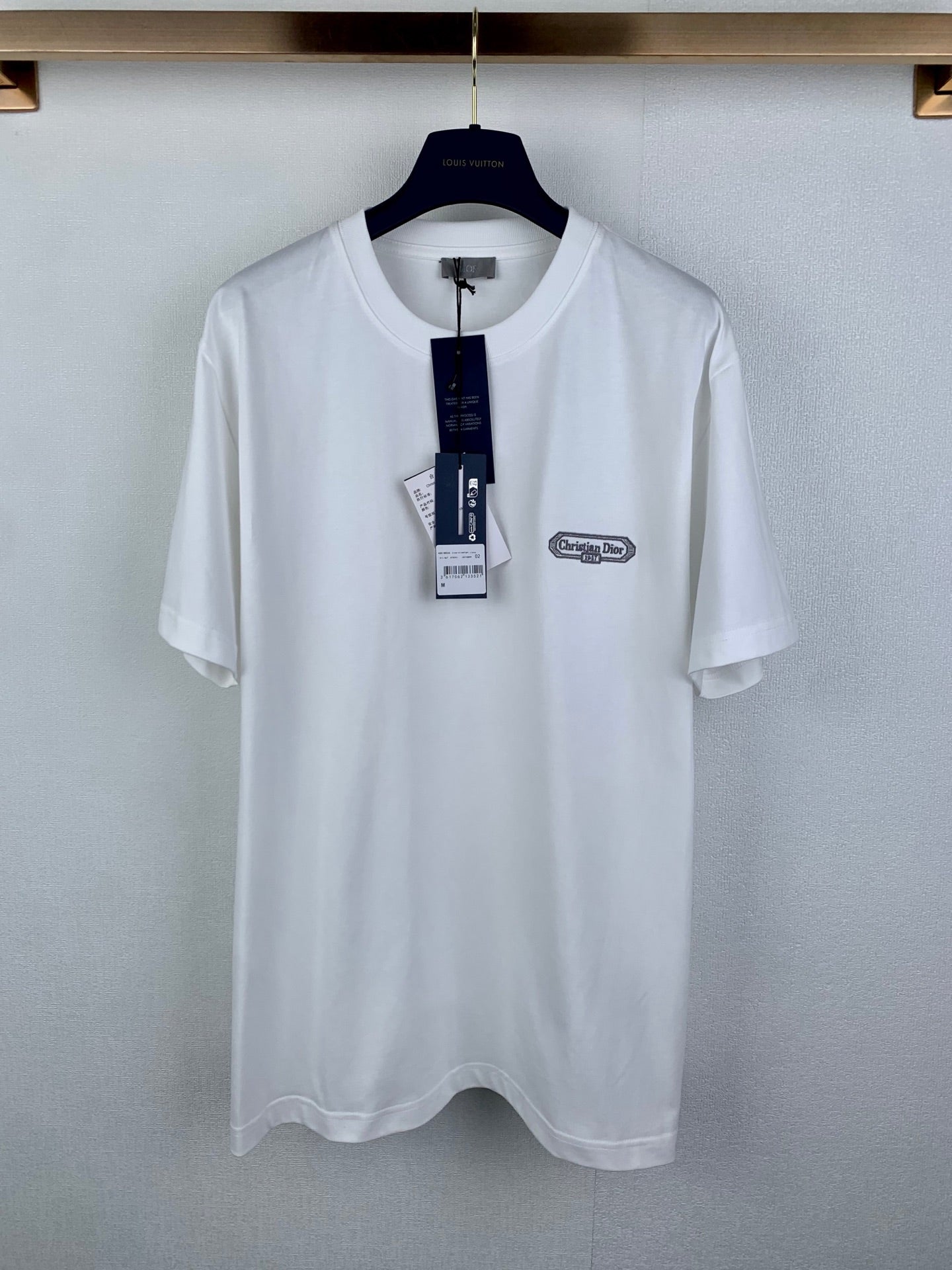 White short-sleeve T-shirt with Dior logo chest patch, on a hanger