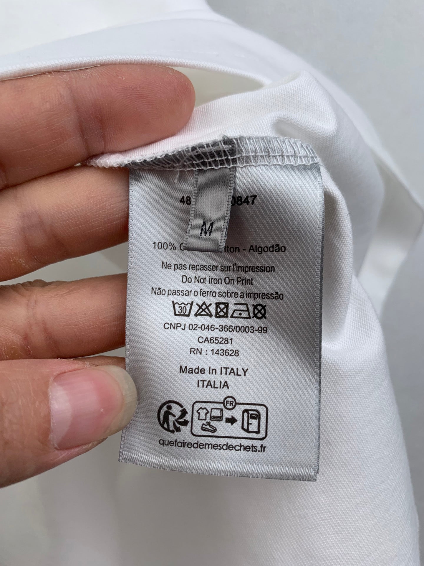 White T-shirt care label showing size M and Made in Italy