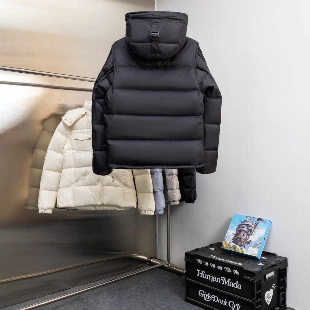 Black hooded puffer jacket on hanger, front view with zipper and padded quilting