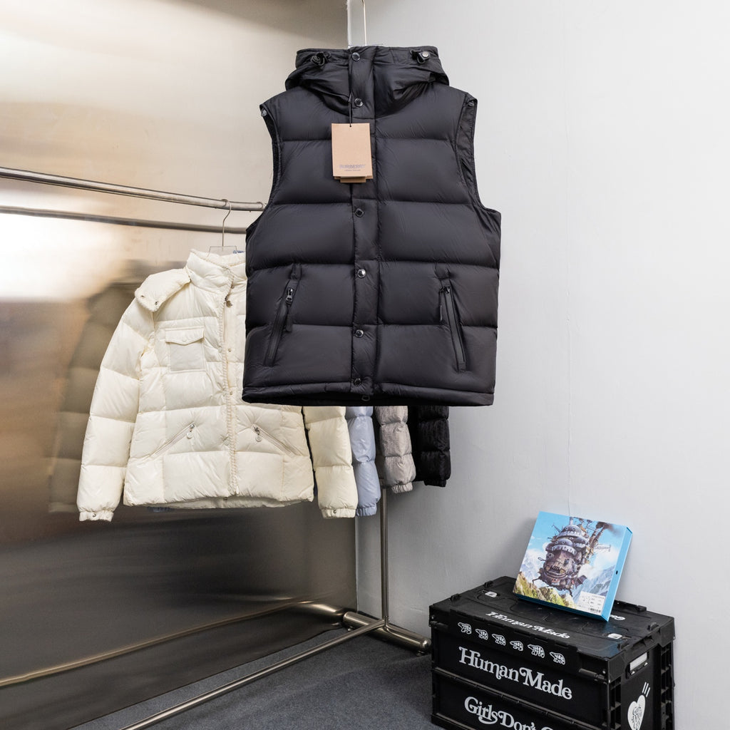 Black padded sleeveless vest with hood and front snap placket on a hanger