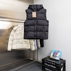 Black padded sleeveless vest with hood and front snap placket on a hanger