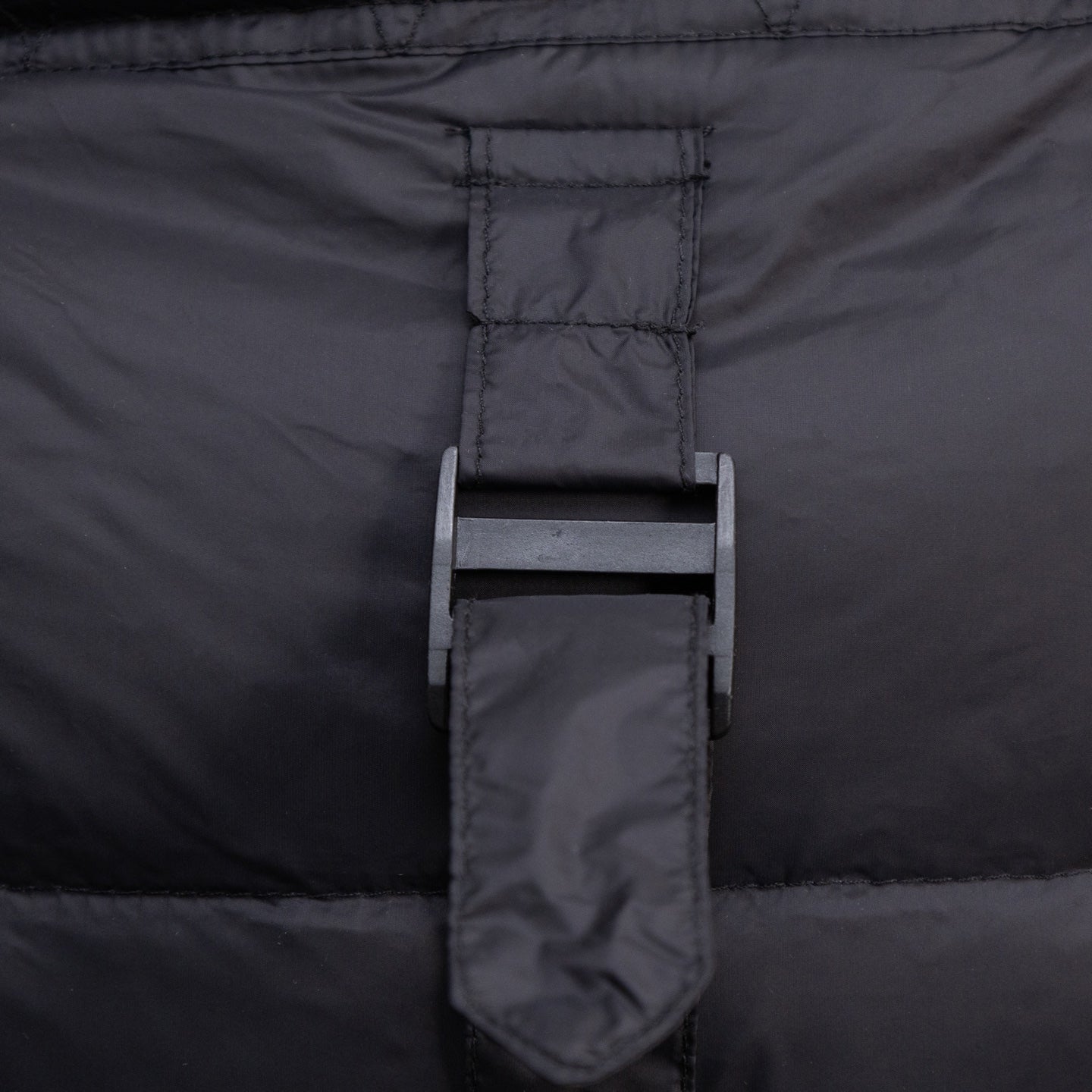 Black puffer vest back yoke with hanging hood tie and central label tag