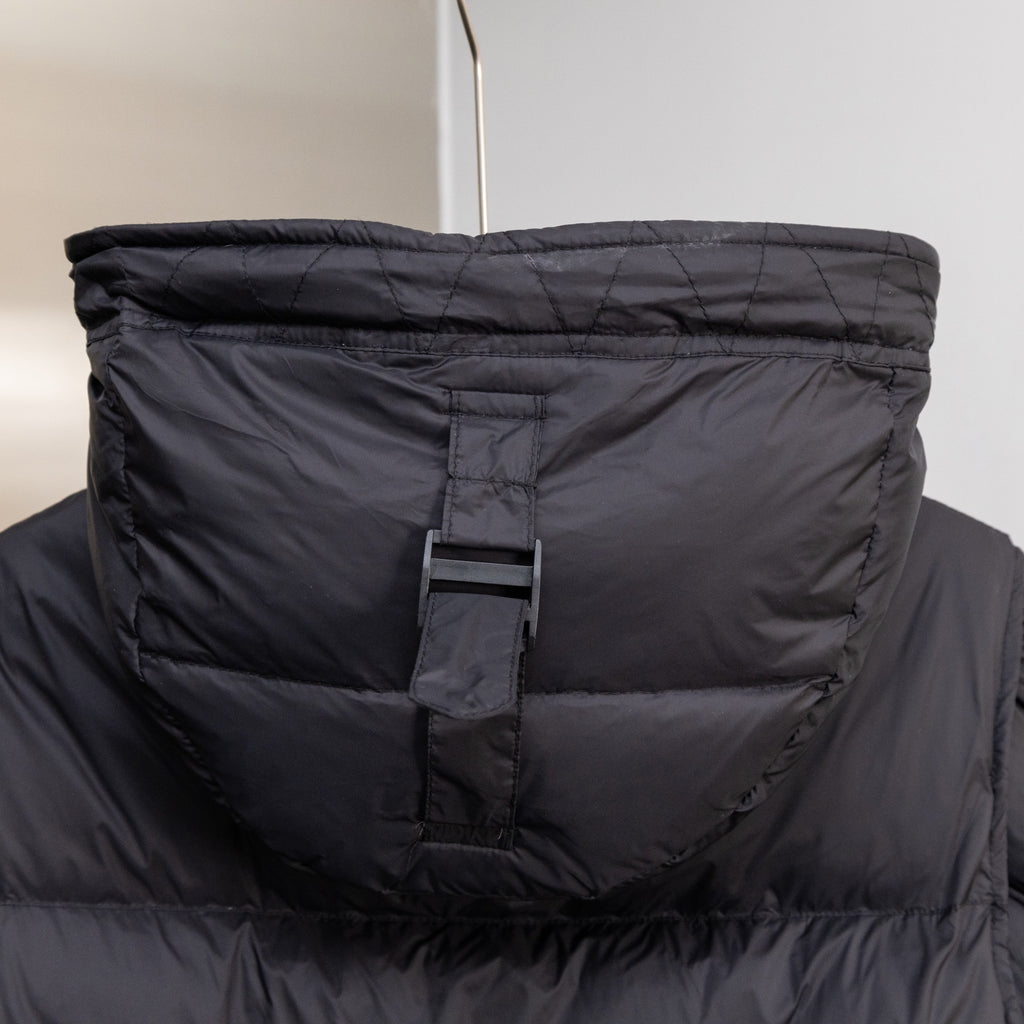 Black puffer vest with hood, front placket, and logo tag at the neckline