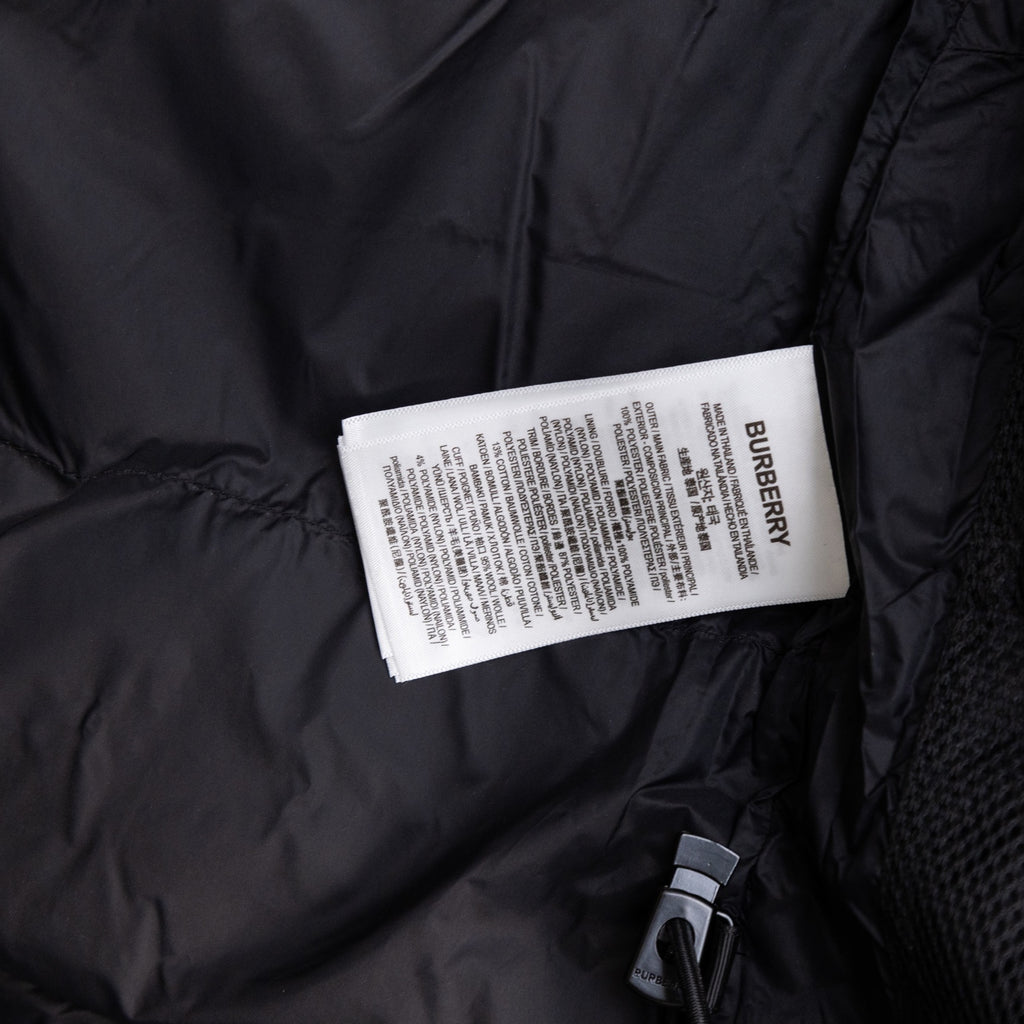 Long black puffer jacket showing Burberry fabric tag and zip pocket