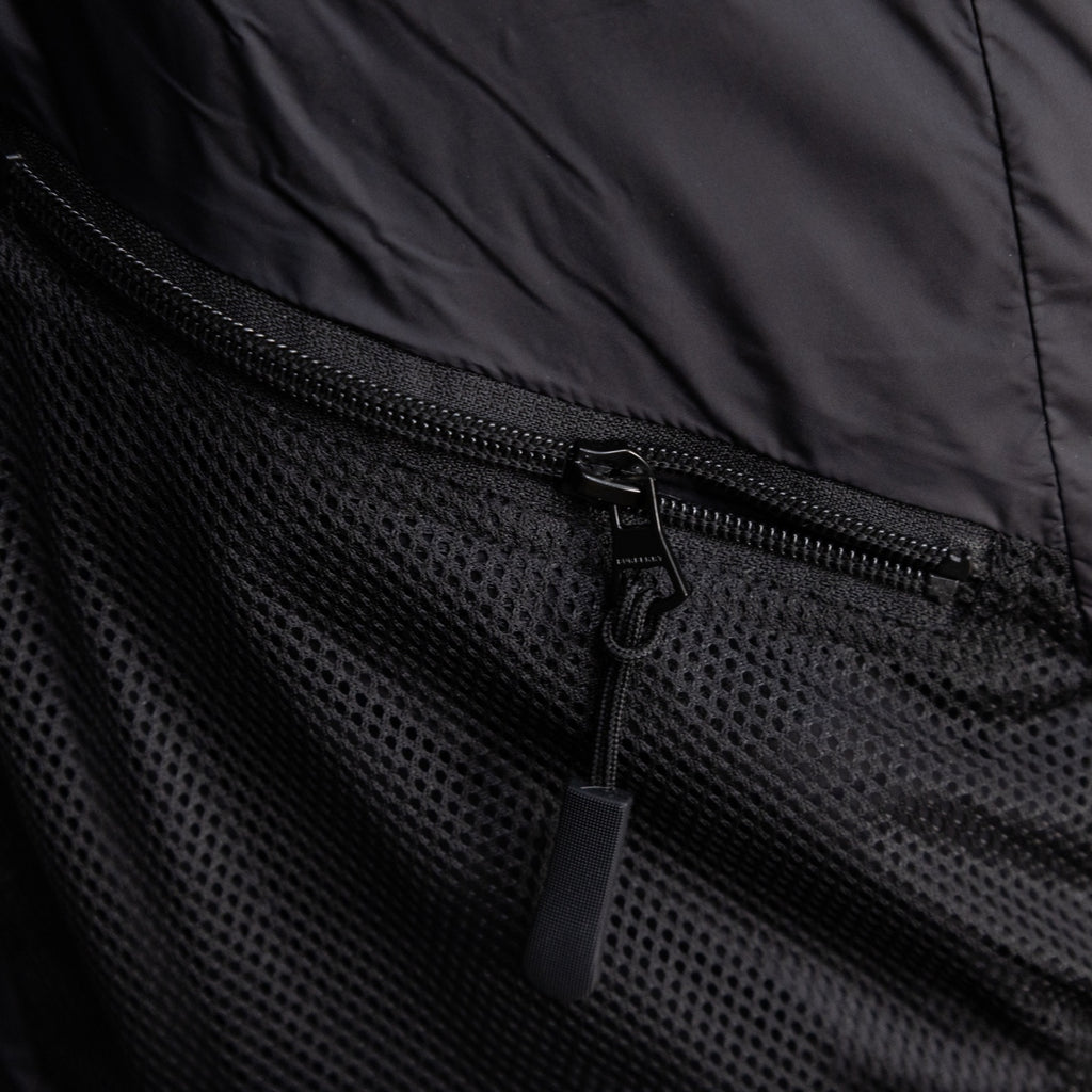 Black puffer vest pocket with mesh fabric and exposed zipper pull