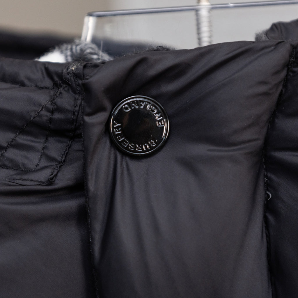 Black puffer jacket shoulder with circular embossed logo patch detail