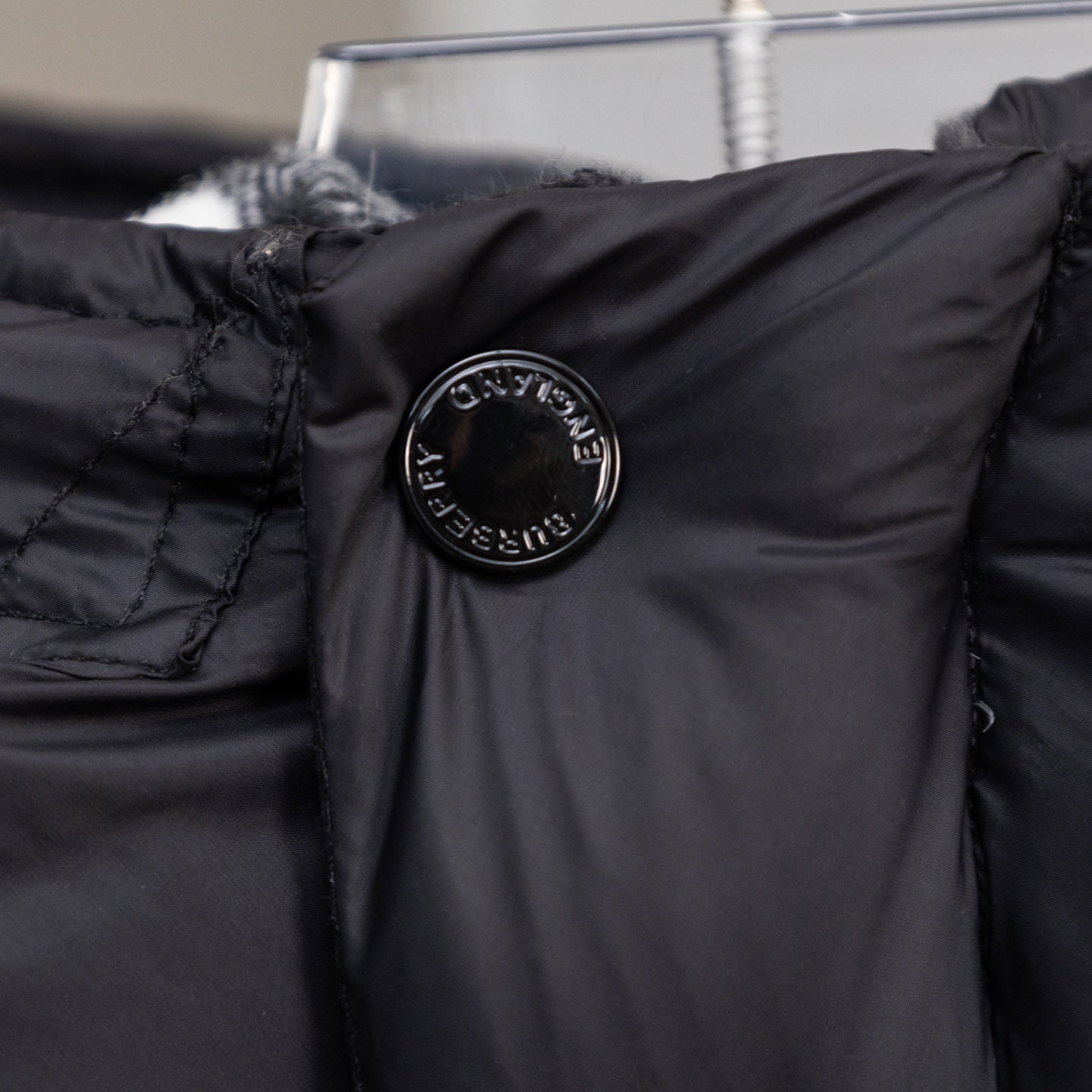 Black puffer jacket shoulder with circular embossed logo patch detail