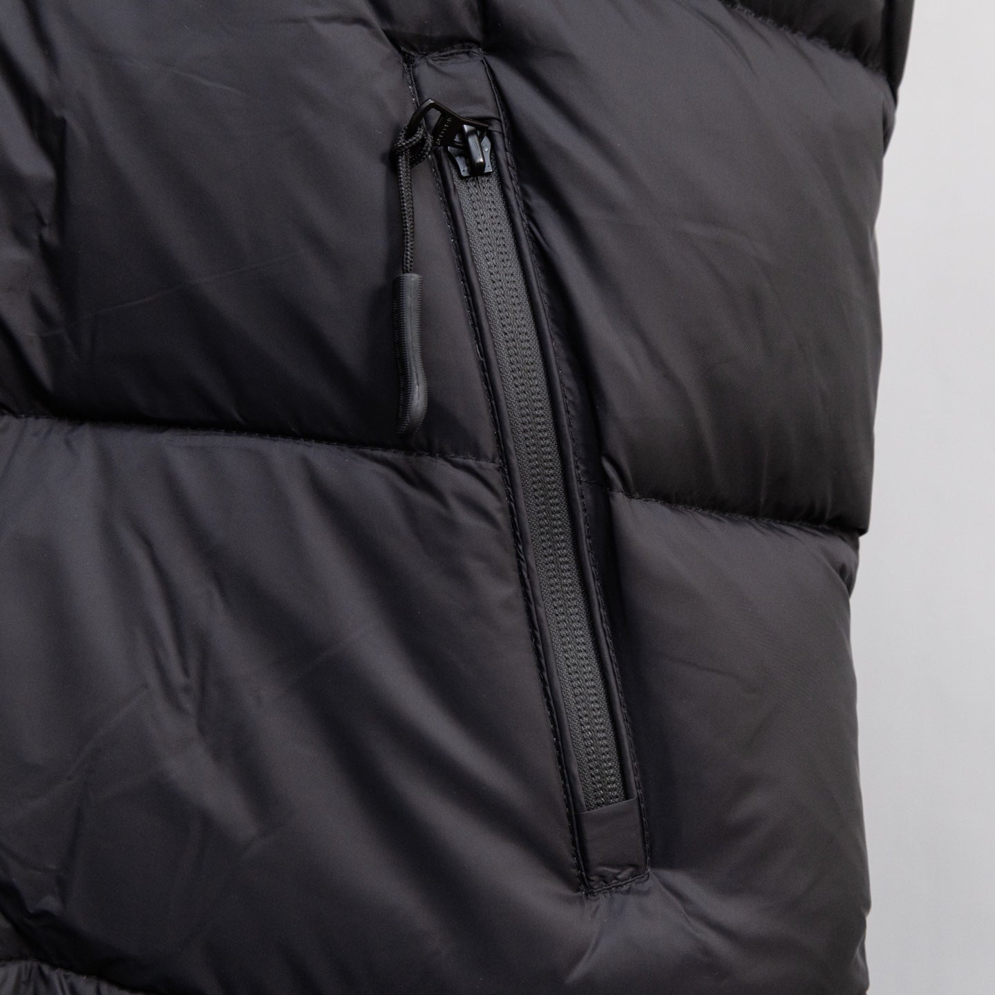 Black sleeveless puffer vest with center front zipper and seam details